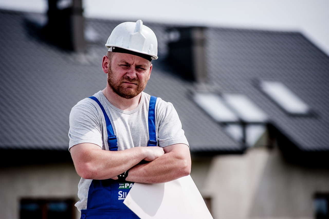 Builder standing with arms folded holding a piece of paper